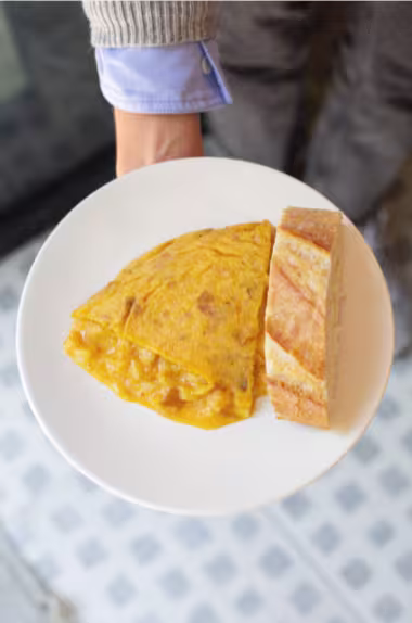 Tortilla de patata de La Bientirada, servida con pan fresco, destacando su textura jugosa y sabor tradicional.