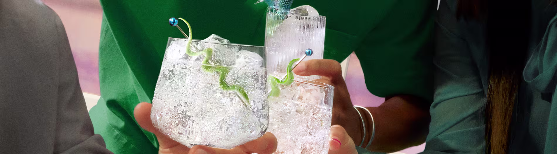 Primer plano de cócteles de ginebra servidos con giros cítricos y hielo en un vibrante ambiente social