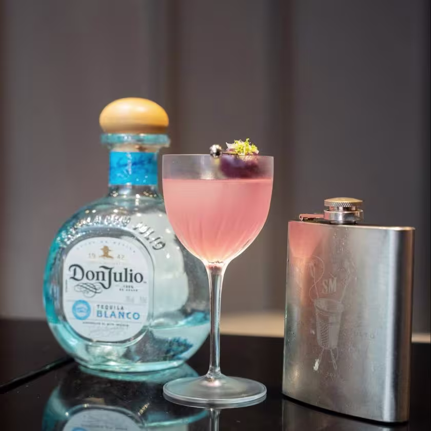 La imagen muestra una botella de tequila Don Julio Blanco junto a un vaso con un cóctel llamado “Fahrenheit 1942” creado por el bartender finalista de World Class 2024 Perú, Mauricio de la Puente.