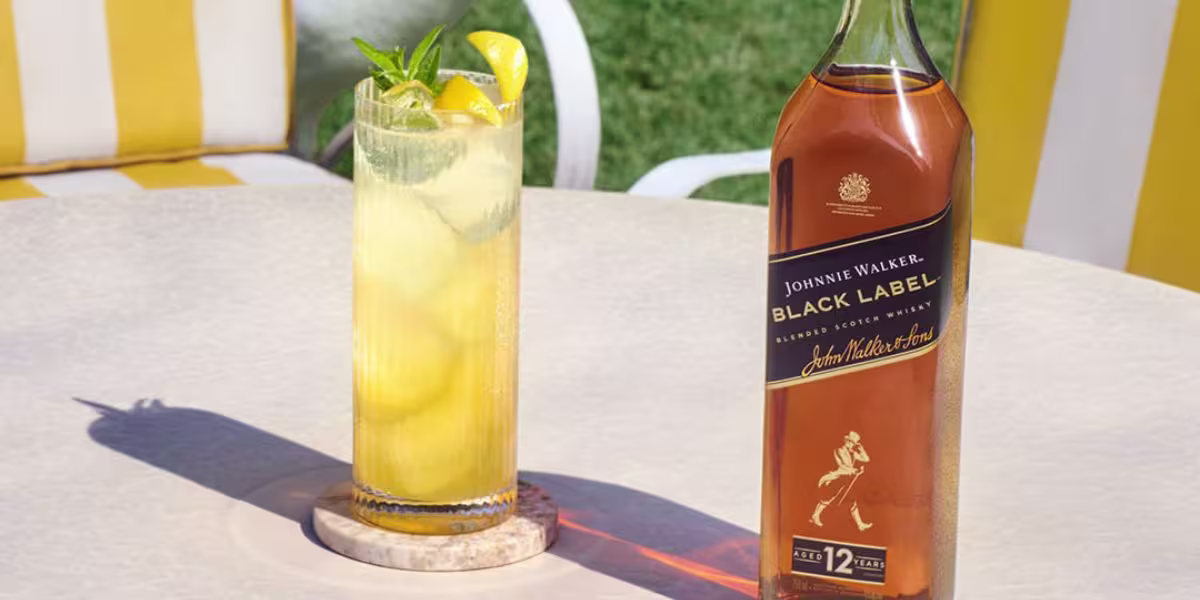 Bottles of Johnnie Walker whisky, including Black Label and Blonde variants, are displayed on a table with other bottles in the background.