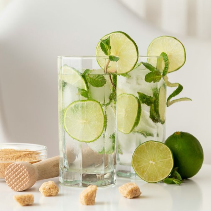 Două mojito non-alcoolice cu garnitură de roată de lime și frunze de mentă.