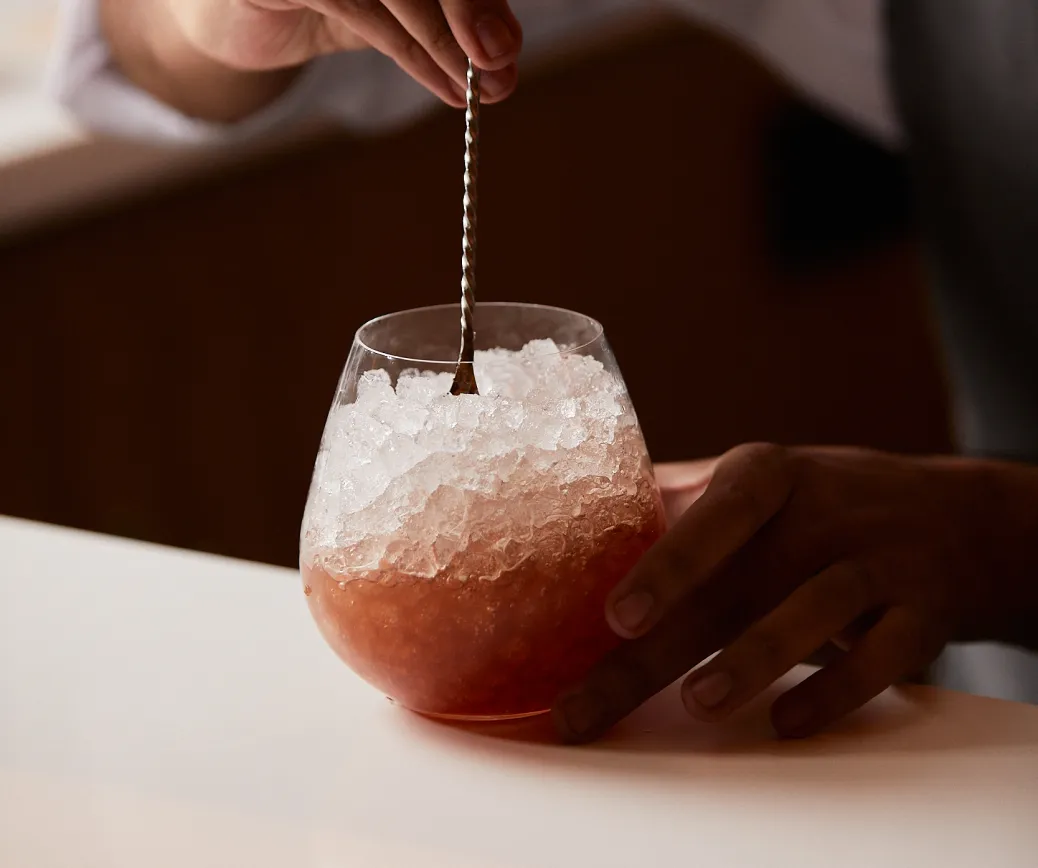 coctel rojizo con hielos picados en un vaso pequeño