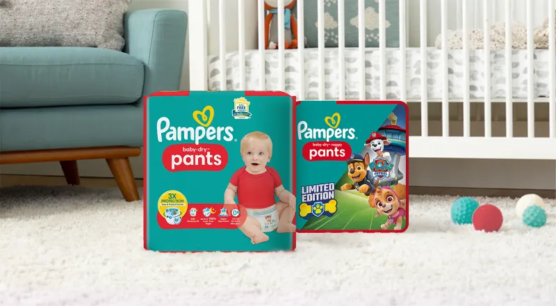 Pampers Baby-Dry Pants und Baby-Dry Paw Patrol Pants Packungen in einem Babyzimmer.