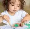 Kleinkind bastelt mit Laubblättern und Wasserfarben 