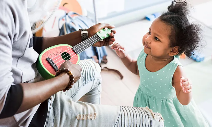 Baby Musik: Vater spielt auf Gitarre für Kleinkind