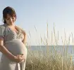 Schwangere Frau am Meer freut sich, denn es wird ein Junge