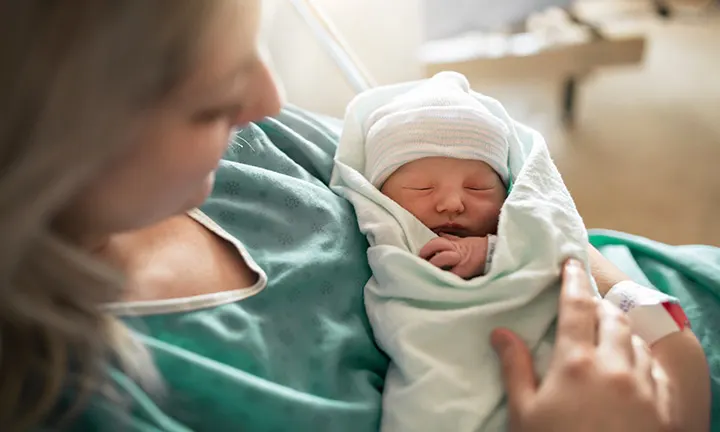 Frau nach natürlicher Geburt hält Baby im Arm