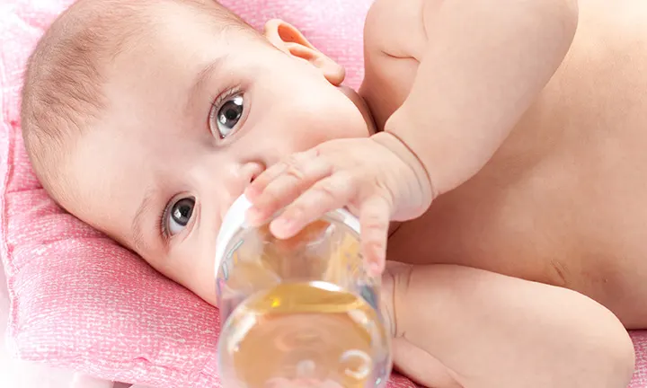 Baby trinkt Tee aus Babyflasche