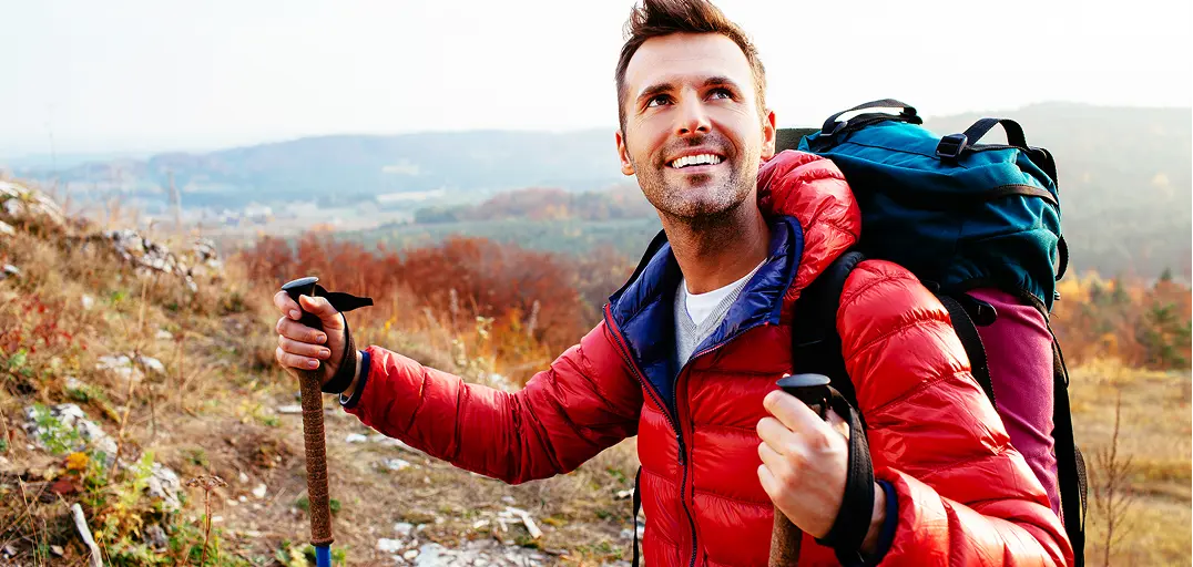 Hiker holding trekking poles with a backpack on a scenic mountain trail