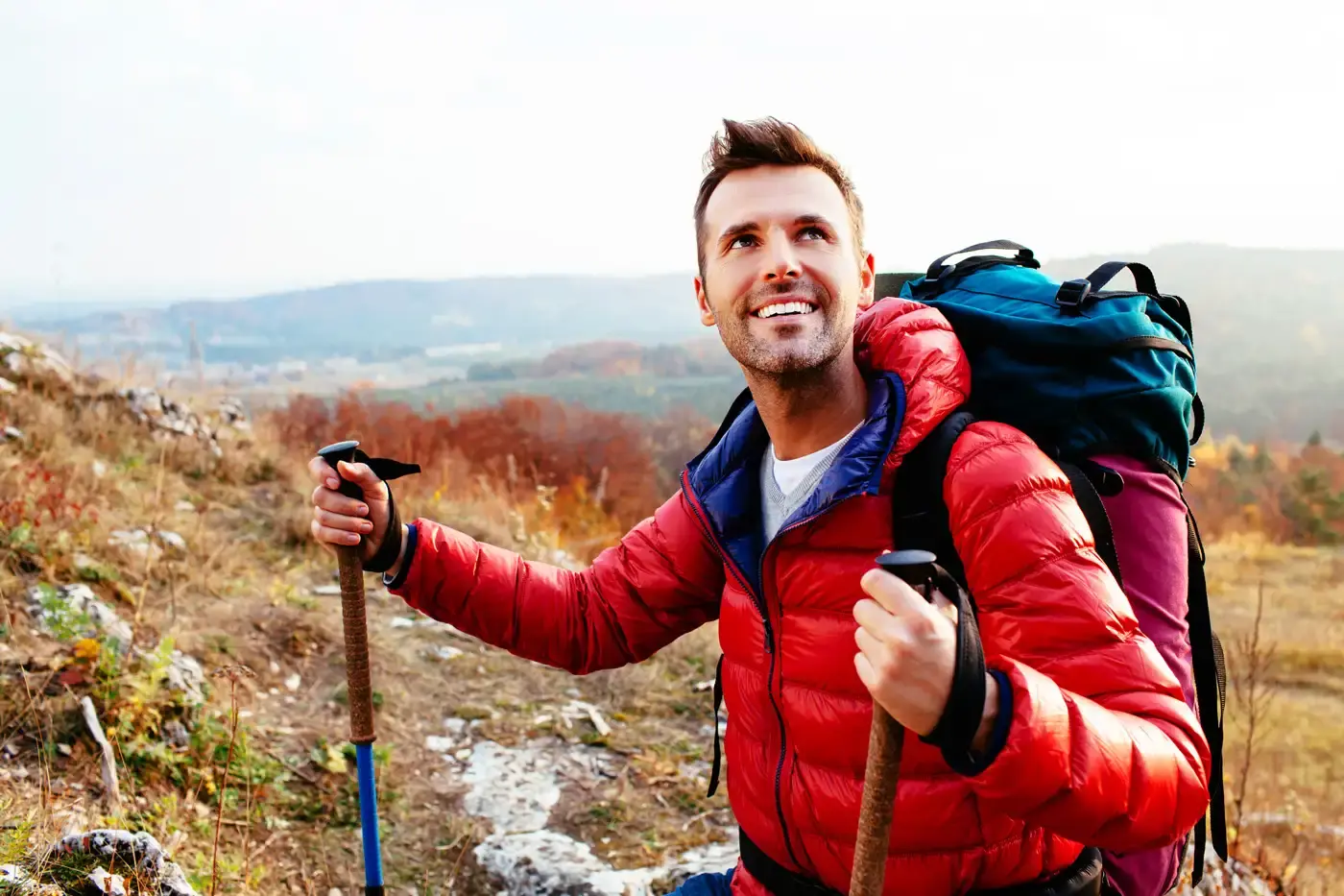 Hiker holding trekking poles with a backpack on a scenic mountain trail