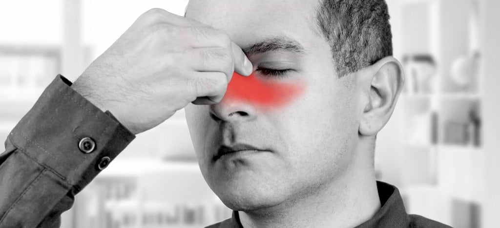 Man holding the bridge of his nose with red highlighted sinus area, indicating sinus pain or headache