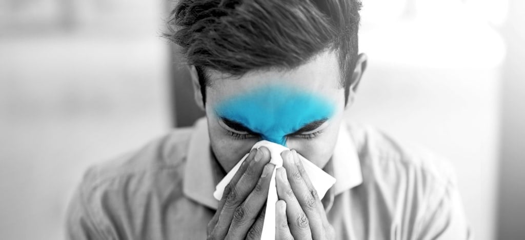 Man experiencing head congestion with highlighted sinus pressure area, blowing his nose due to a runny or stuffy nose