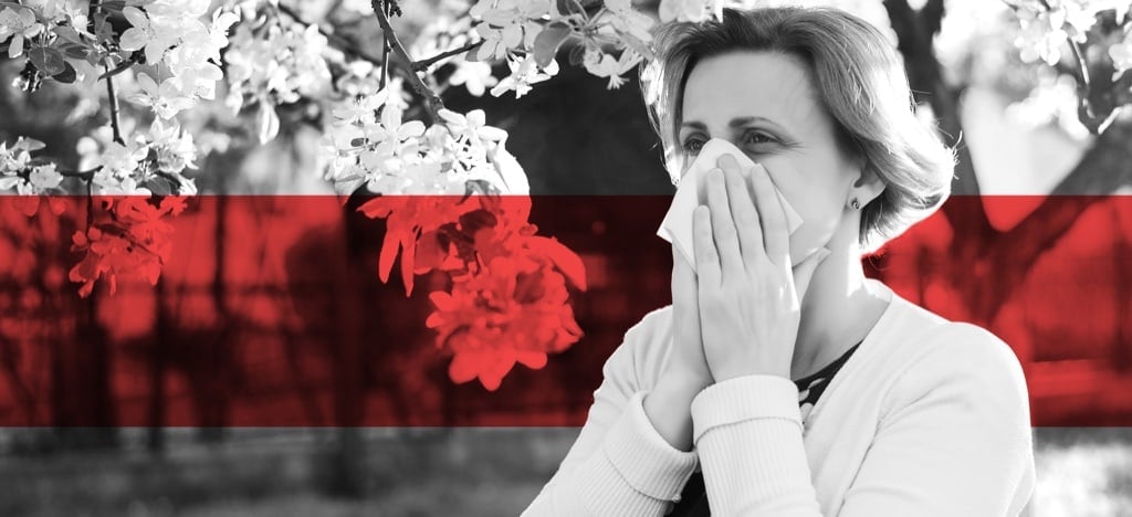 Woman with seasonal allergies sneezing near blooming flowers