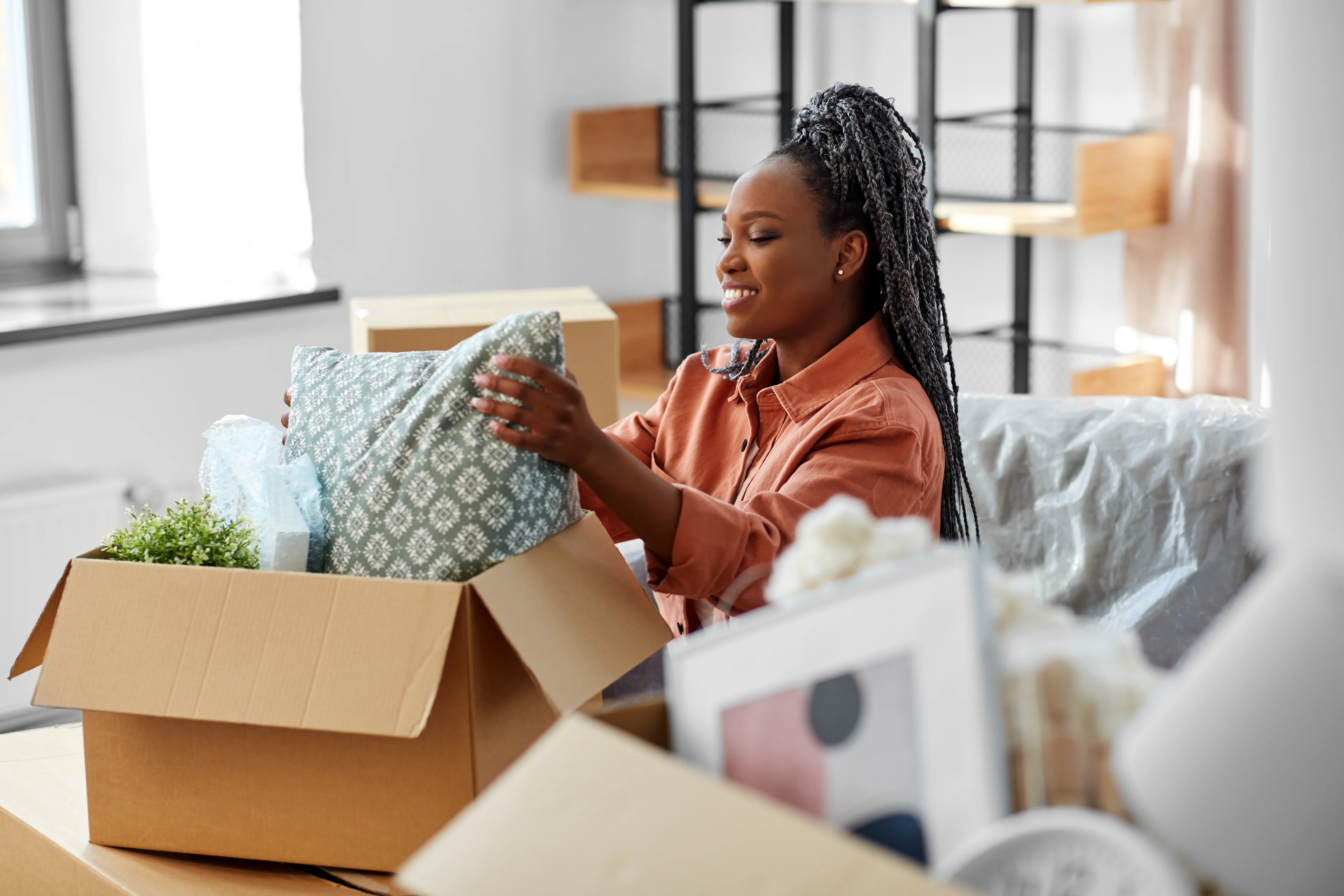 a picture of a woman packing her belongings into a box for a move. 