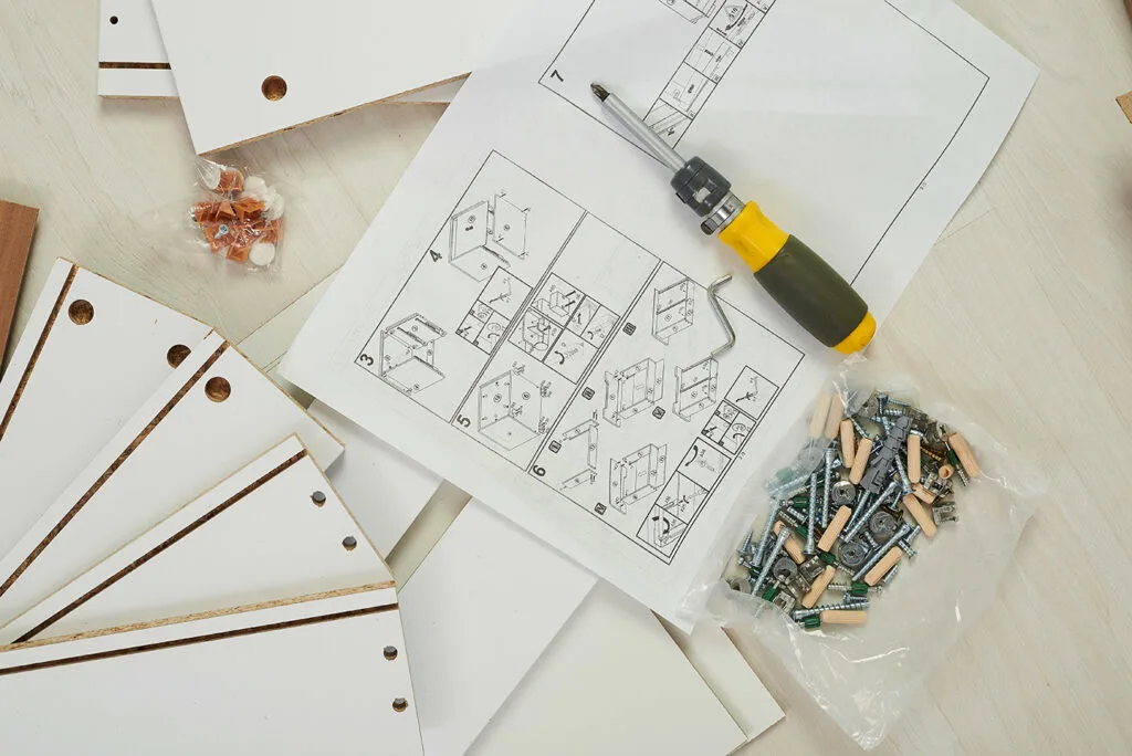 an image of an instruction manual, with a screw driver, and furniture components.