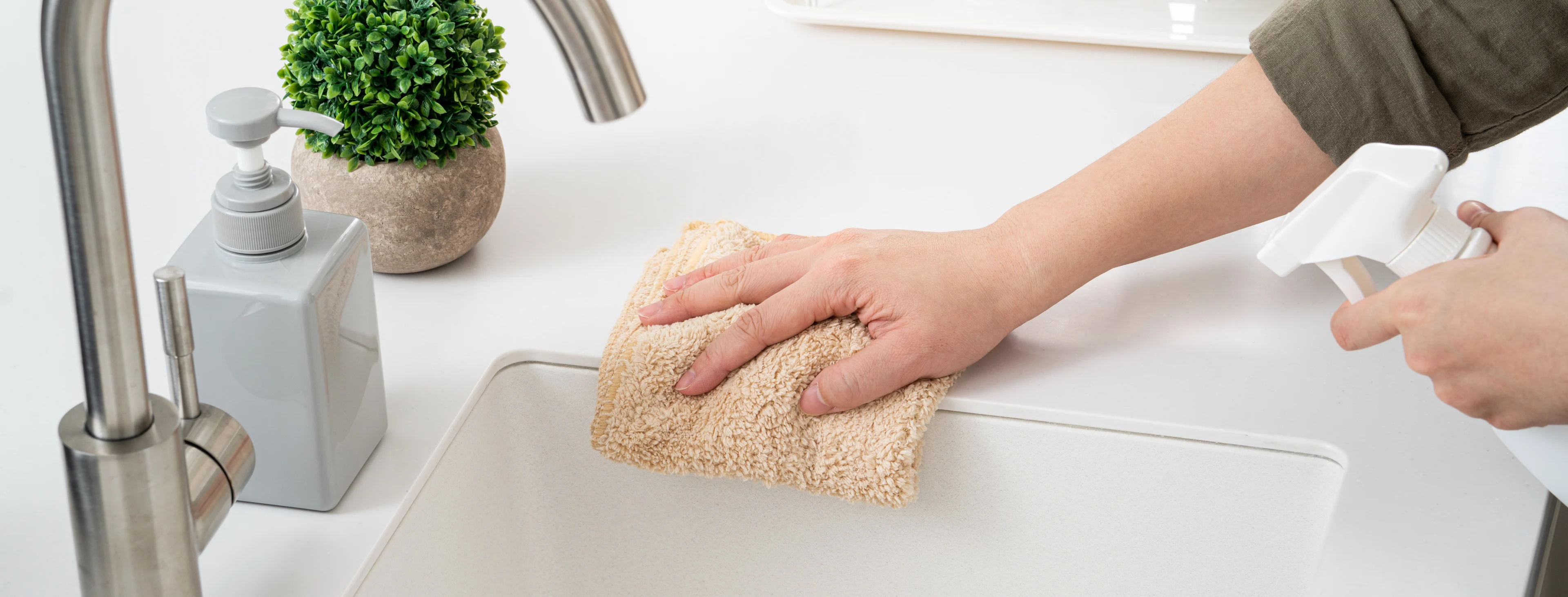 une personne portant un gant nettoie un évier en se servant d’un produit spécifique. 