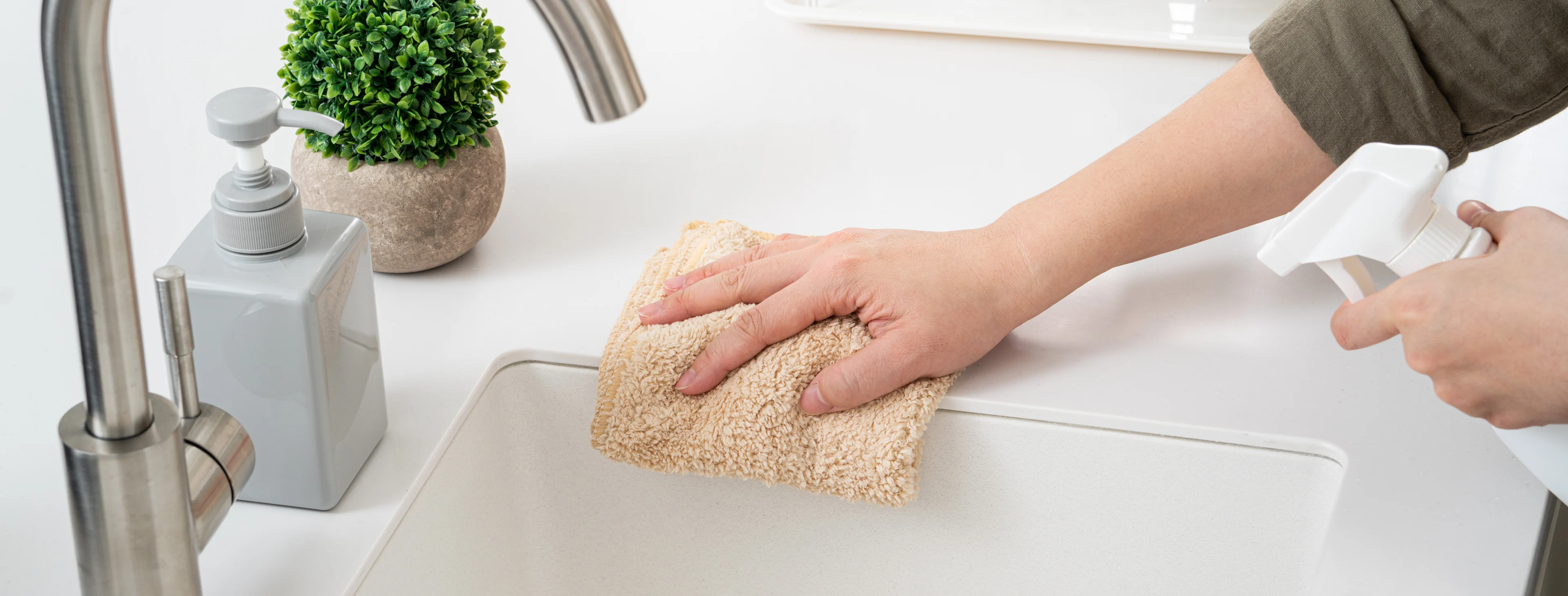 a person cleaning a sink with a cloth and a cleaning bottle. 