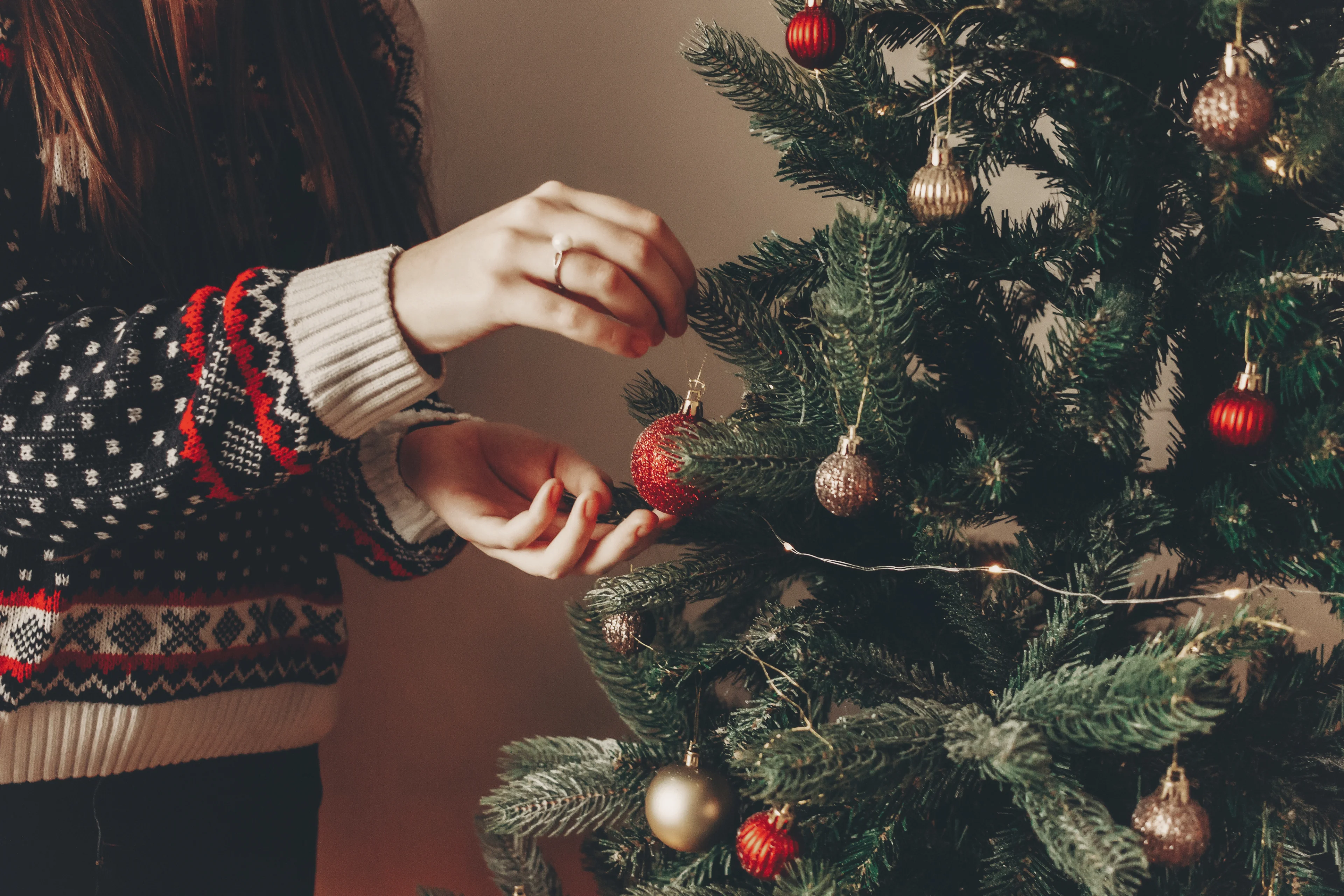 image of a woman hanging ornaments on a christmas tree. 