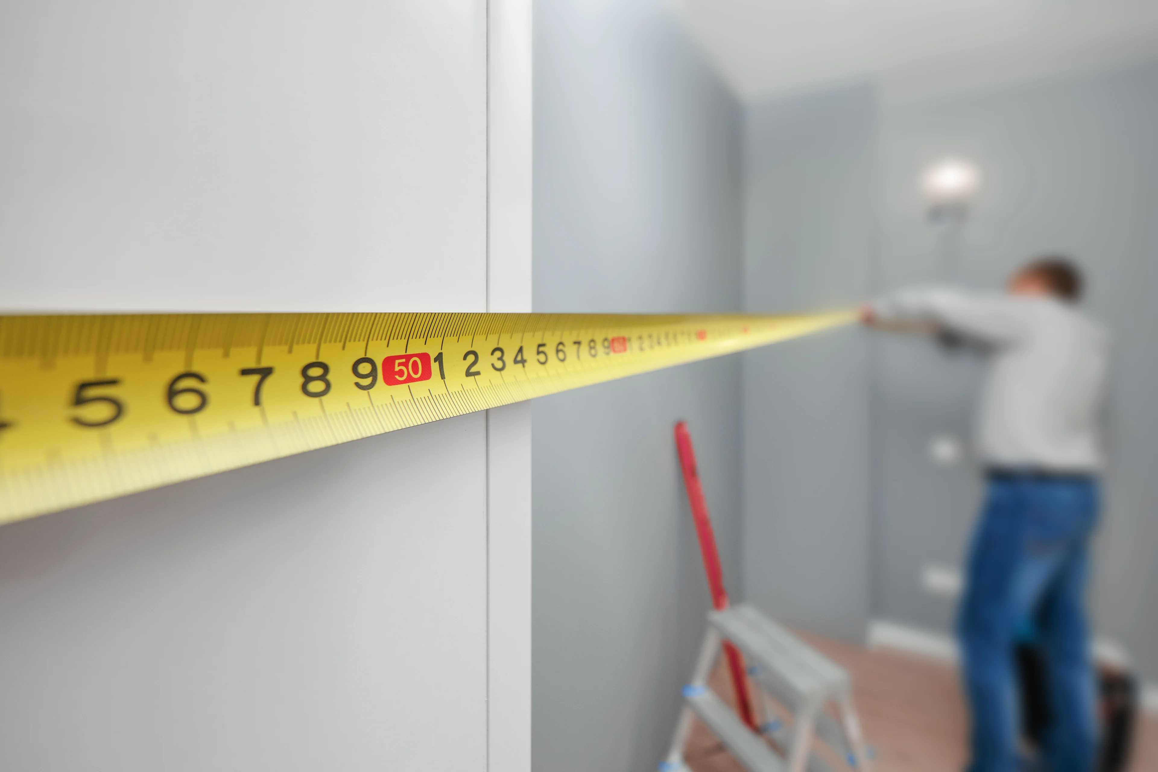 a person using a measuring tape to measure the length of a wall