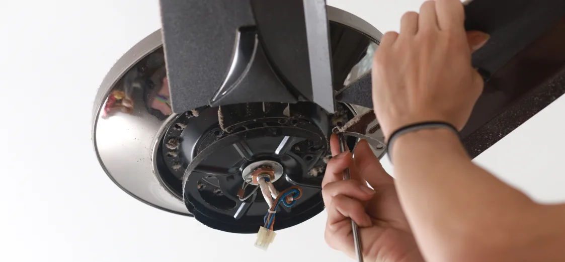 A picture of someone installing a ceiling fan