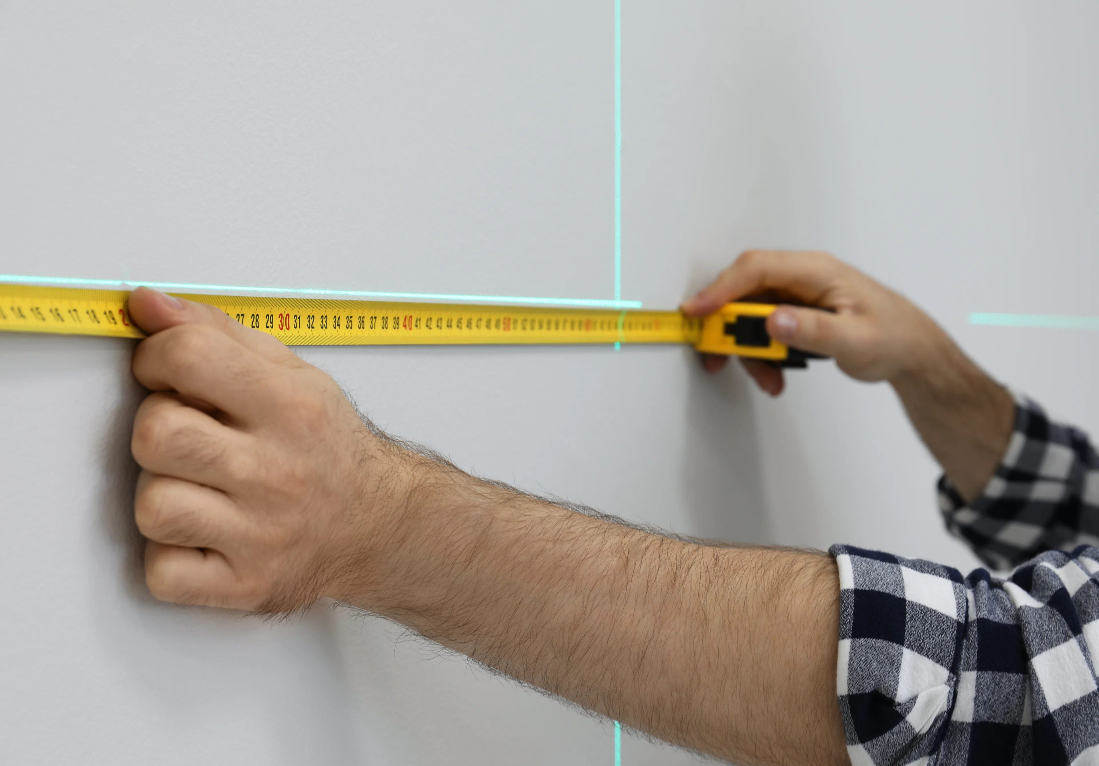 a person measuring and leveling points to drill into a wall to install mounting brackets