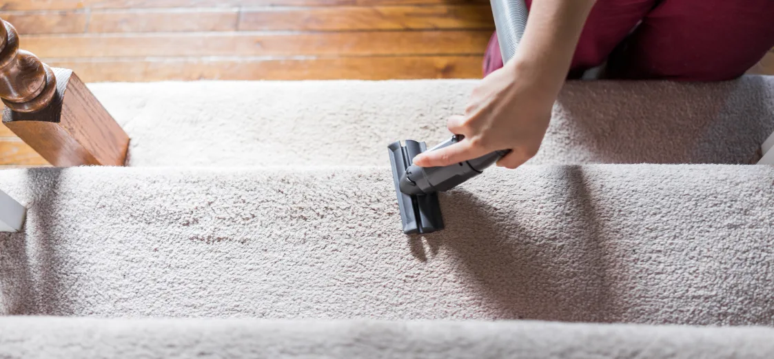 A picture of someone cleaning carpet with a steamer