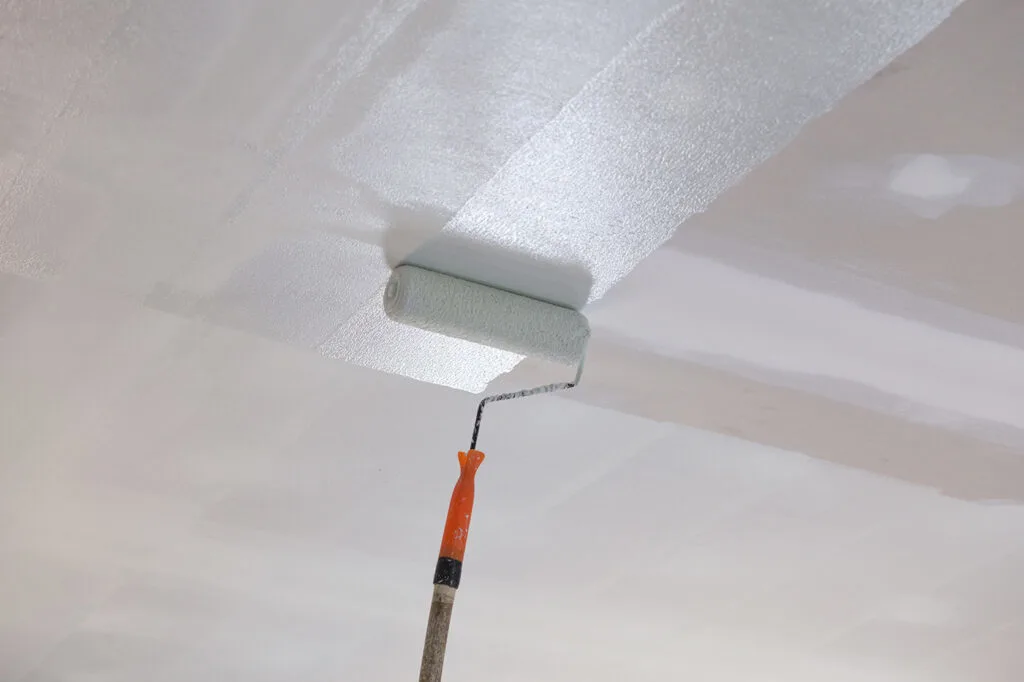 A picture of someone painting a ceiling with a paint roller