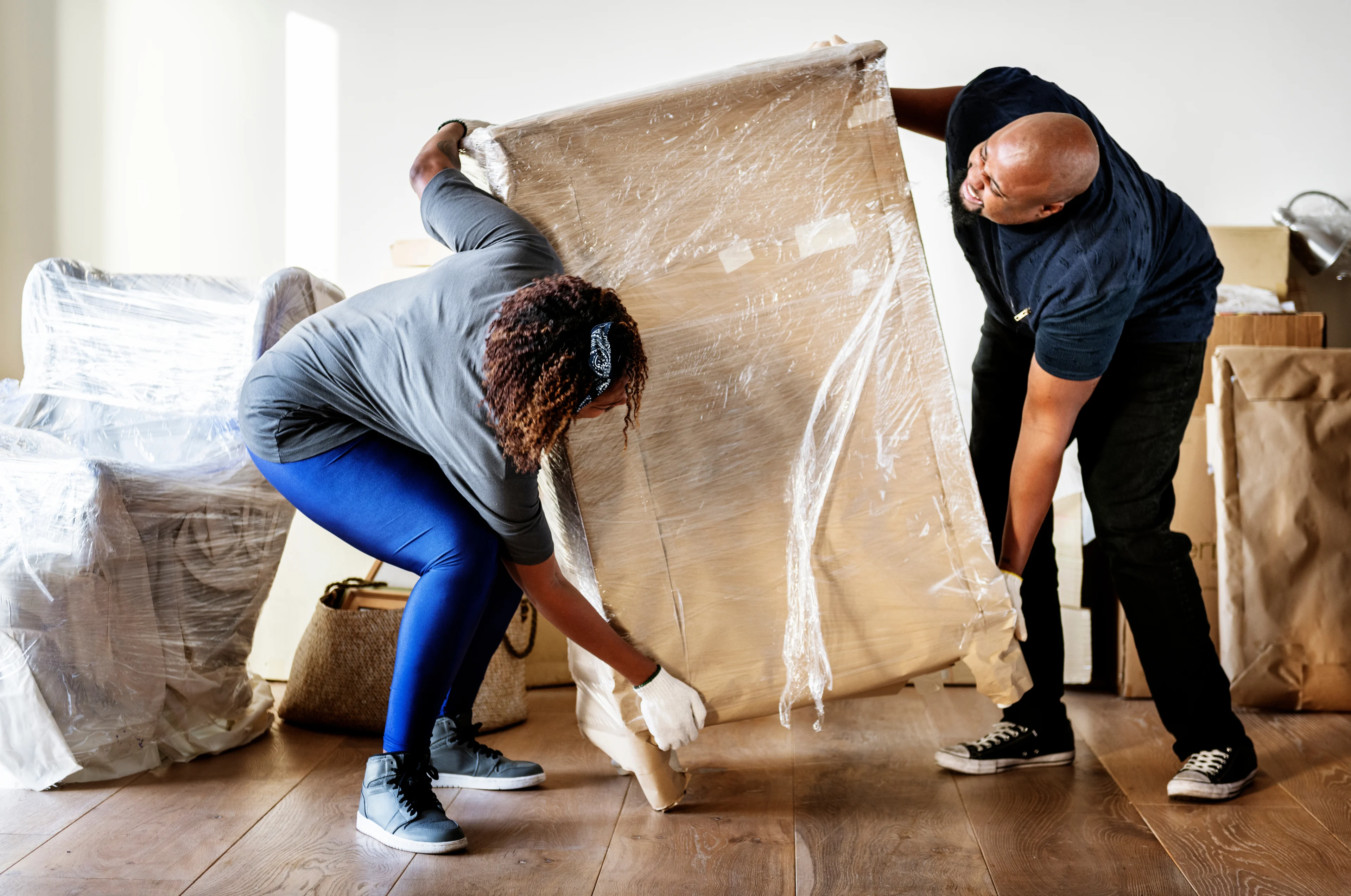 a man and a woman lifting a heavy chest of drawers