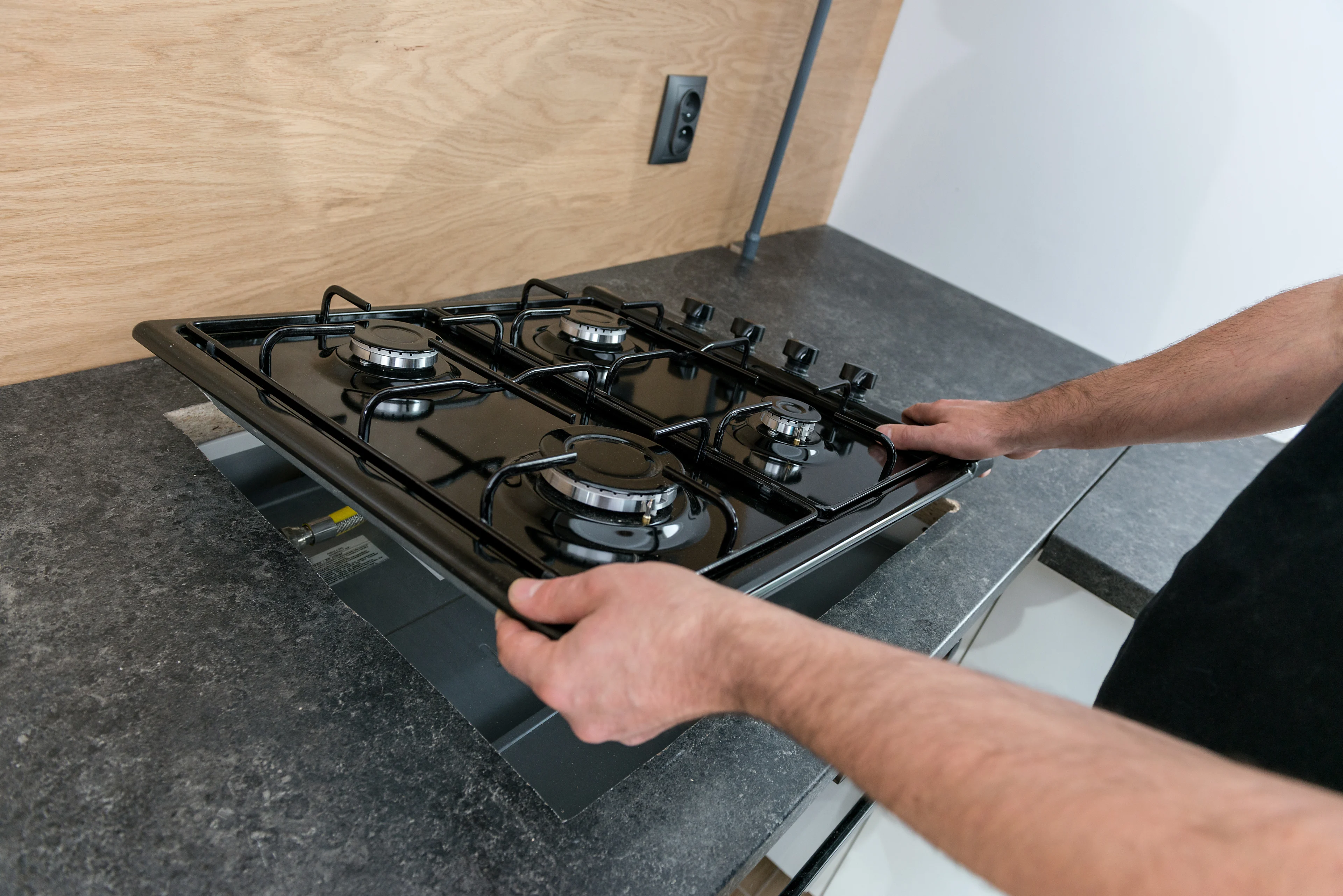 a person installing a gas range into a kitchen counter.