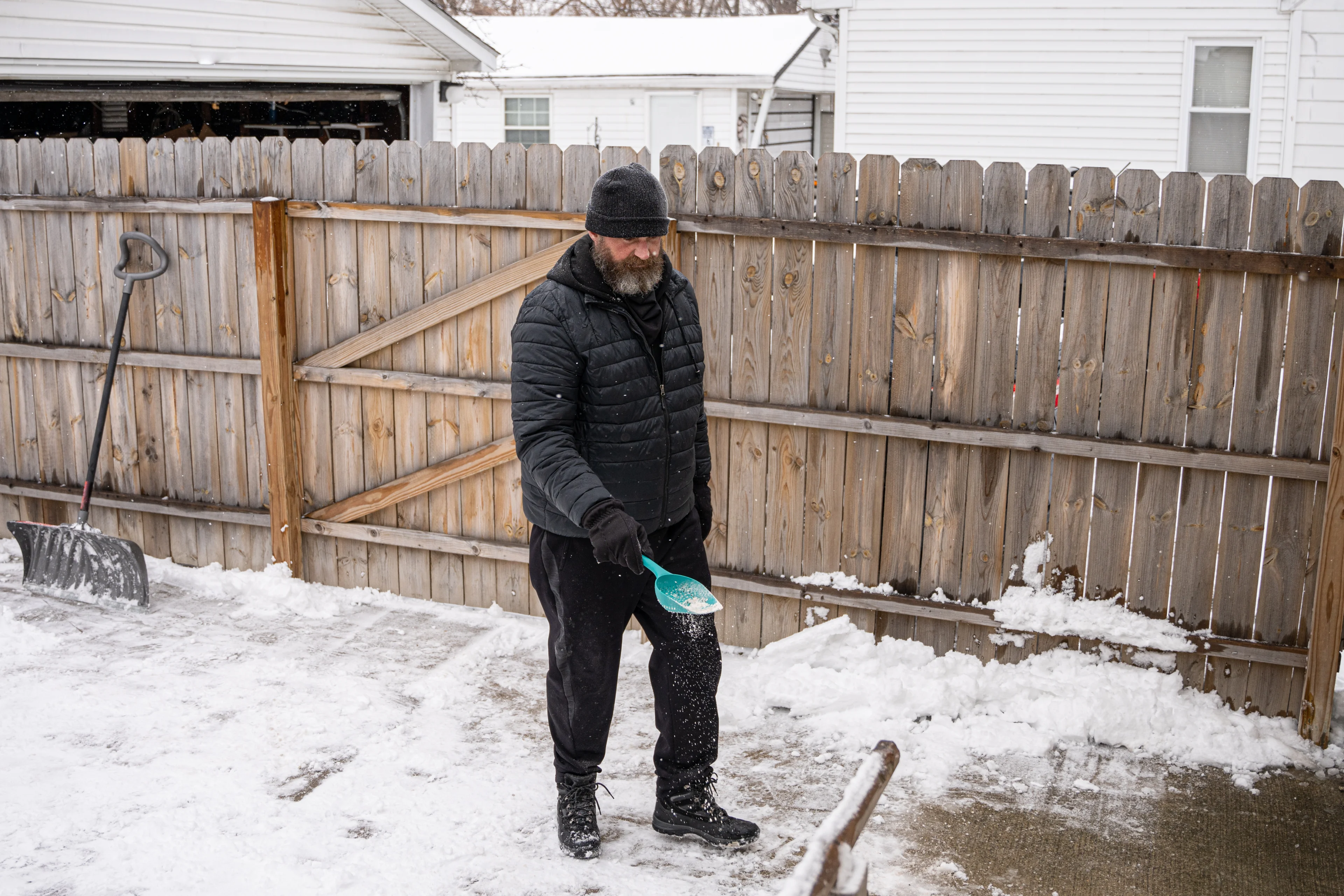 a bearded man salting concrete to melt snow and prevent ice from forming
