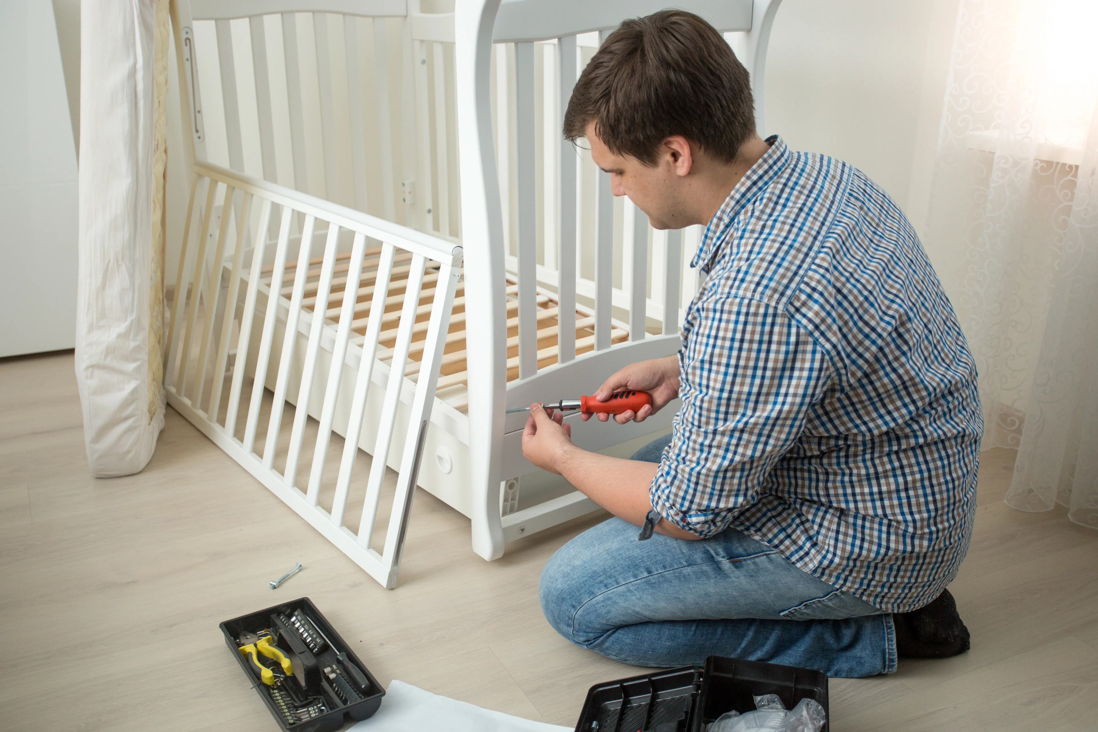 a man disassembling a crib