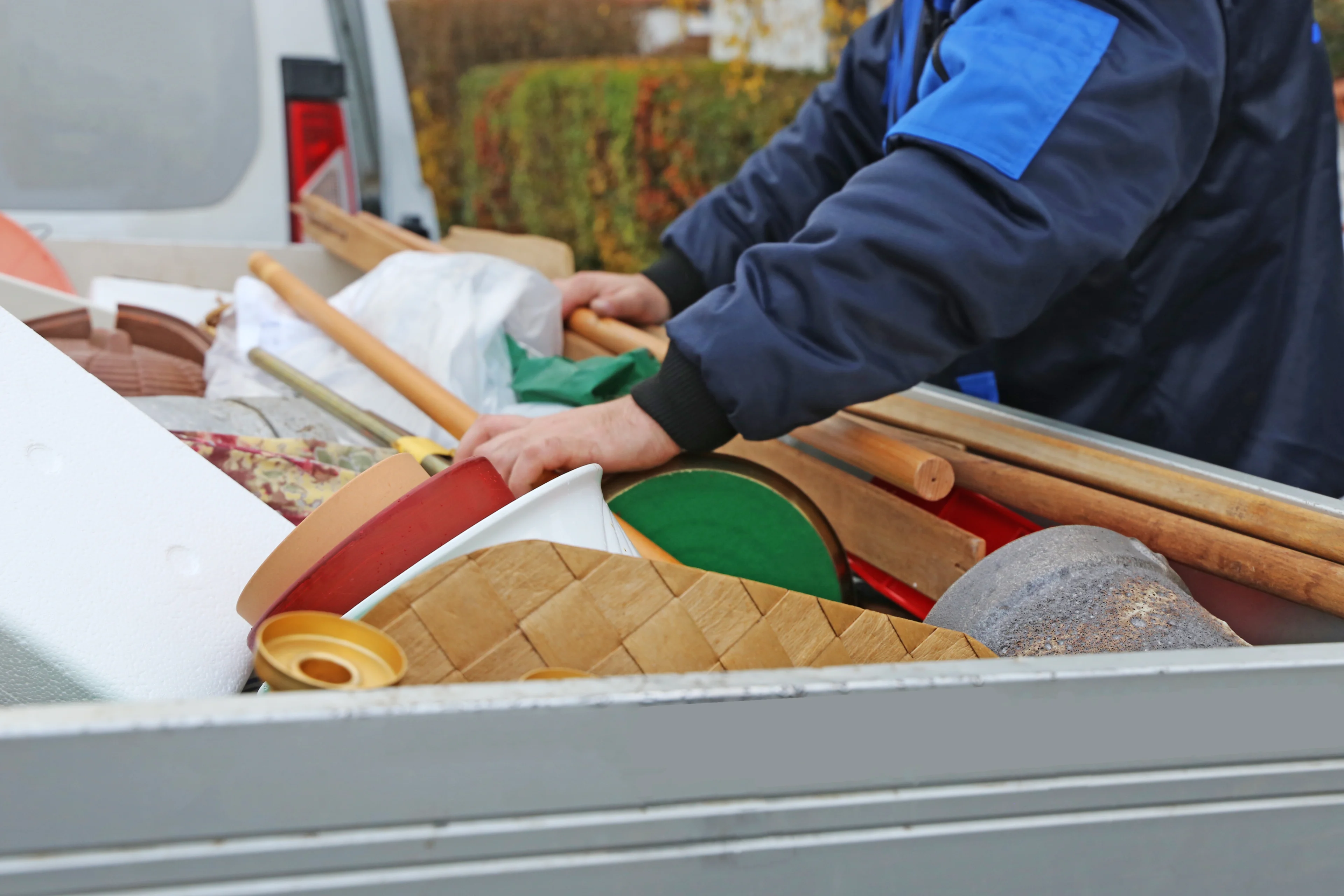 a person loading junk items into the back of a truck to haul away.