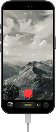 Un iPhone 18 Pro, face avant, affichant un paysage montagneux, avec le menu superposé du mode caméra en mode accéléré, câble d’alimentation branché au port de recharge