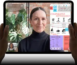 iPad Pro, front exterior, landscape orientation, space black colour, rounded corners, black display bezel, hands holding left and right sides, display showing a FaceTime conversation being live translated, and an educational app showing a presentation of "Comparative Mythology" with text, diagrams and handwritten notes