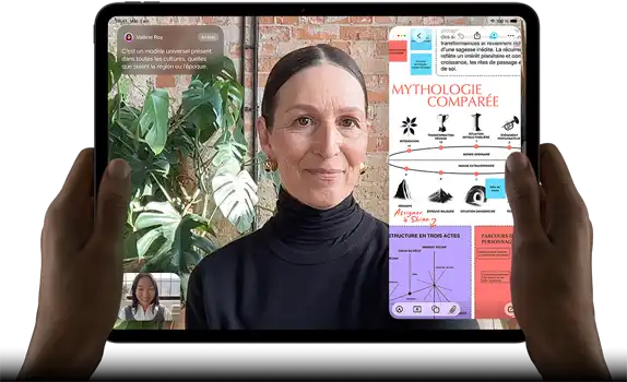 iPad Pro, face avant, orientation paysage, noir infini, coins arrondis, bordure d’écran noire, mains tenant les côtés gauche et droit, écran affichant une conversation FaceTime traduite en direct, et une app éducative montrant une présentation sur la "mythologie comparée" avec du texte, des diagrammes et des notes manuscrites