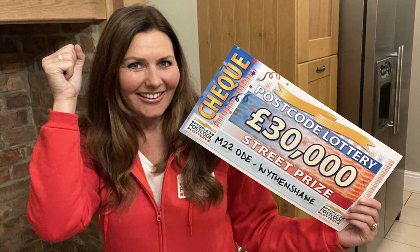 Judie with thrilling £30,000 cheques for our Wythenshawe winners