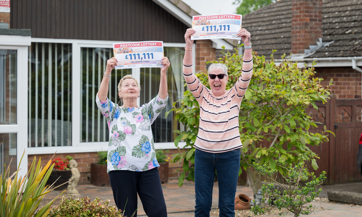 Next door neighbours Olga and Linda hold their winning cheques aloft