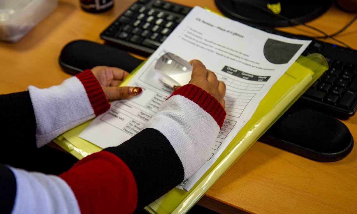 A partially sighted person uses a lense to read a document