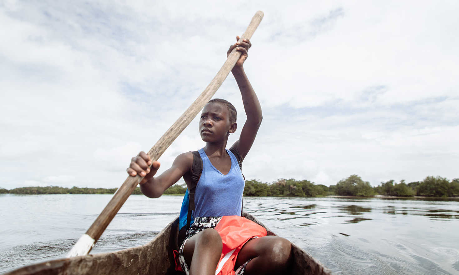 Tenneh, aged 13, paddling her wooden canoe to school in Pujehun district, Sierra Leone. 
