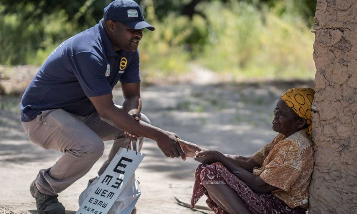 Holding an 'E-chart', Sightsavers community eye health worker Mai Mai greets a woman