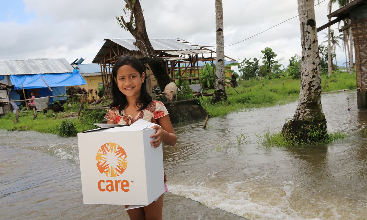 Jeannie Nola receiving a CARE package shortly after Typhoon Haiyan, with flooded fields all around