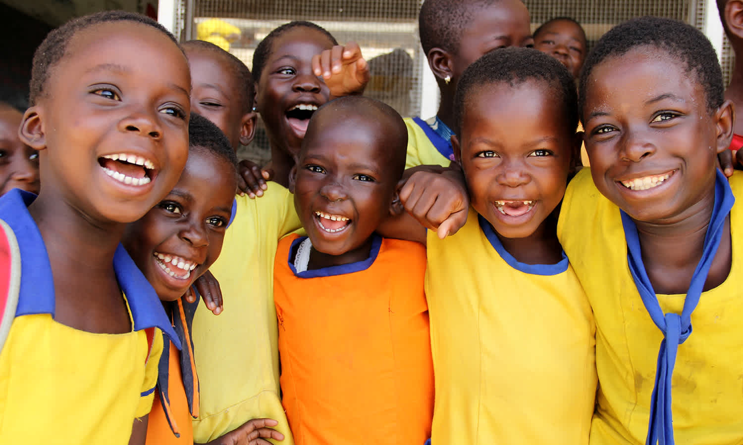 Afrikids. A group of laughing school-aged children in orange-yellow uniforms