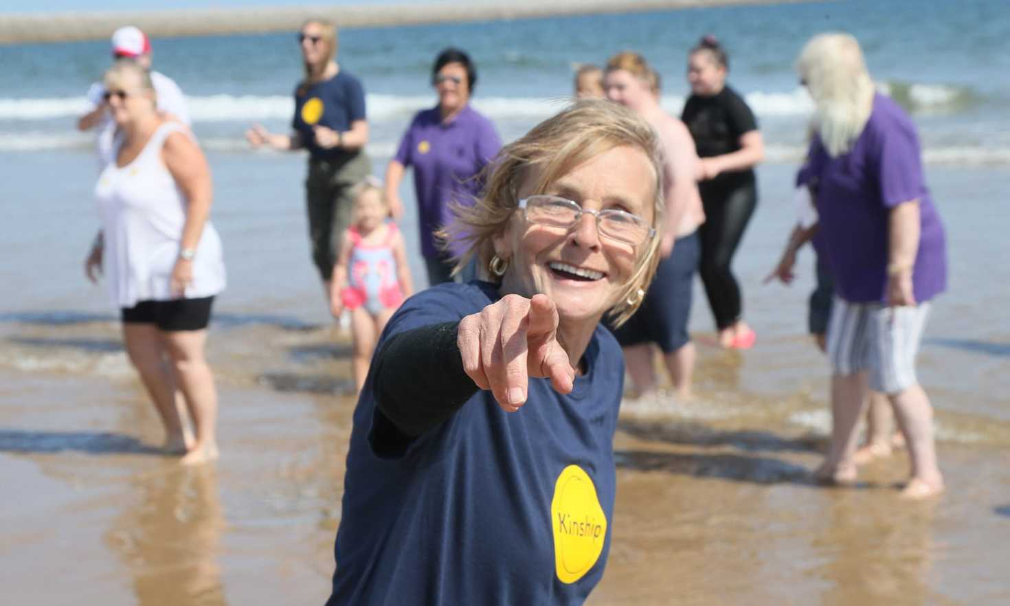 Kinship carers paddling at the beach with children