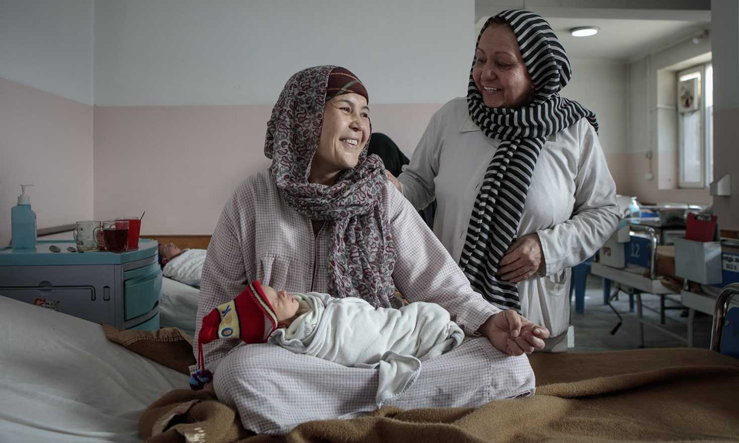New mother Zakia holds one of her twins in the maternity wing of Dasht-e-Barchi hospital in Kabul as an MSF midwife checks on her. (Photo credit/copyright Sandra Calligaro)