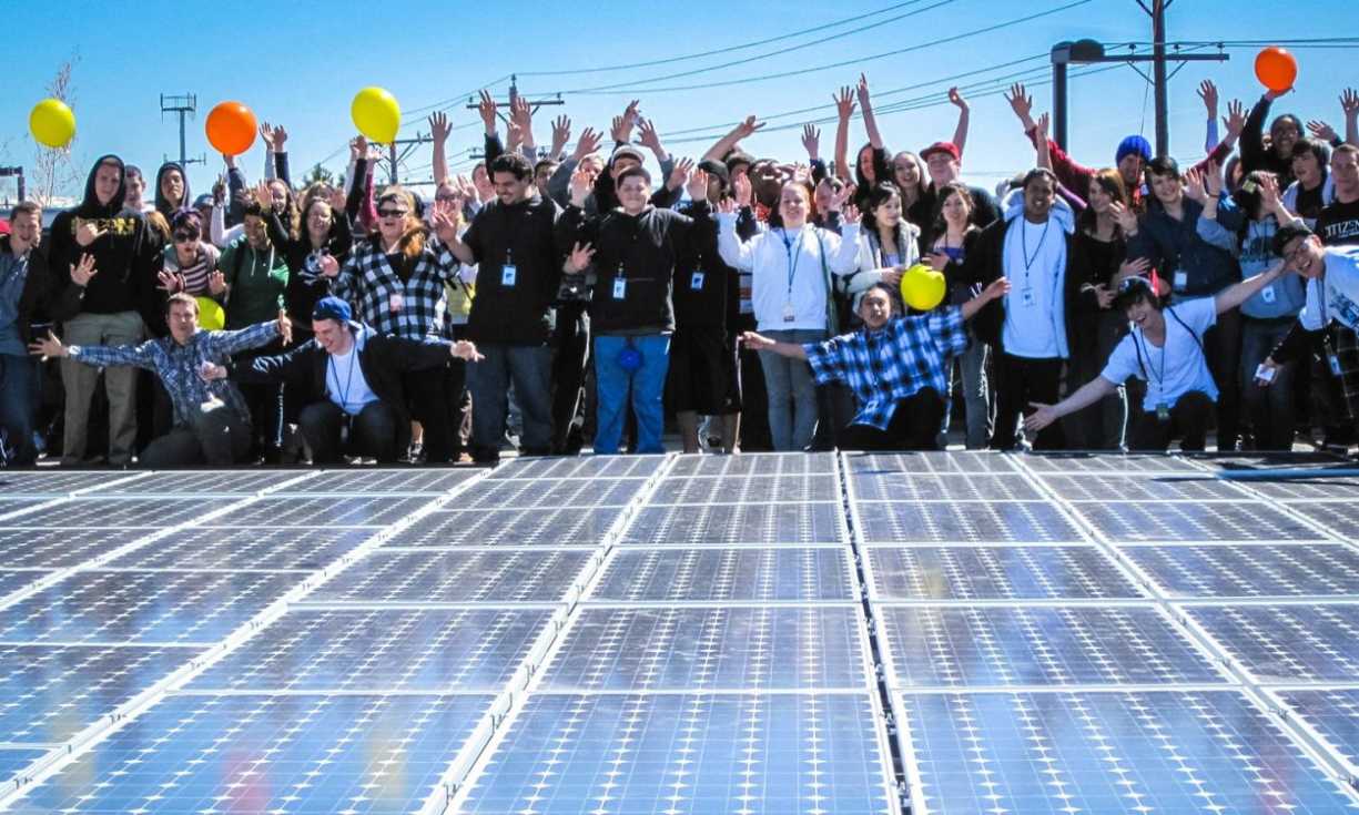 Supporters of renewable energy release balloons next to a large group of solar panels