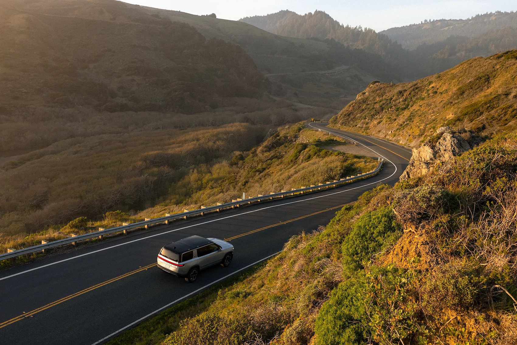 Rivian driving in between mountains.