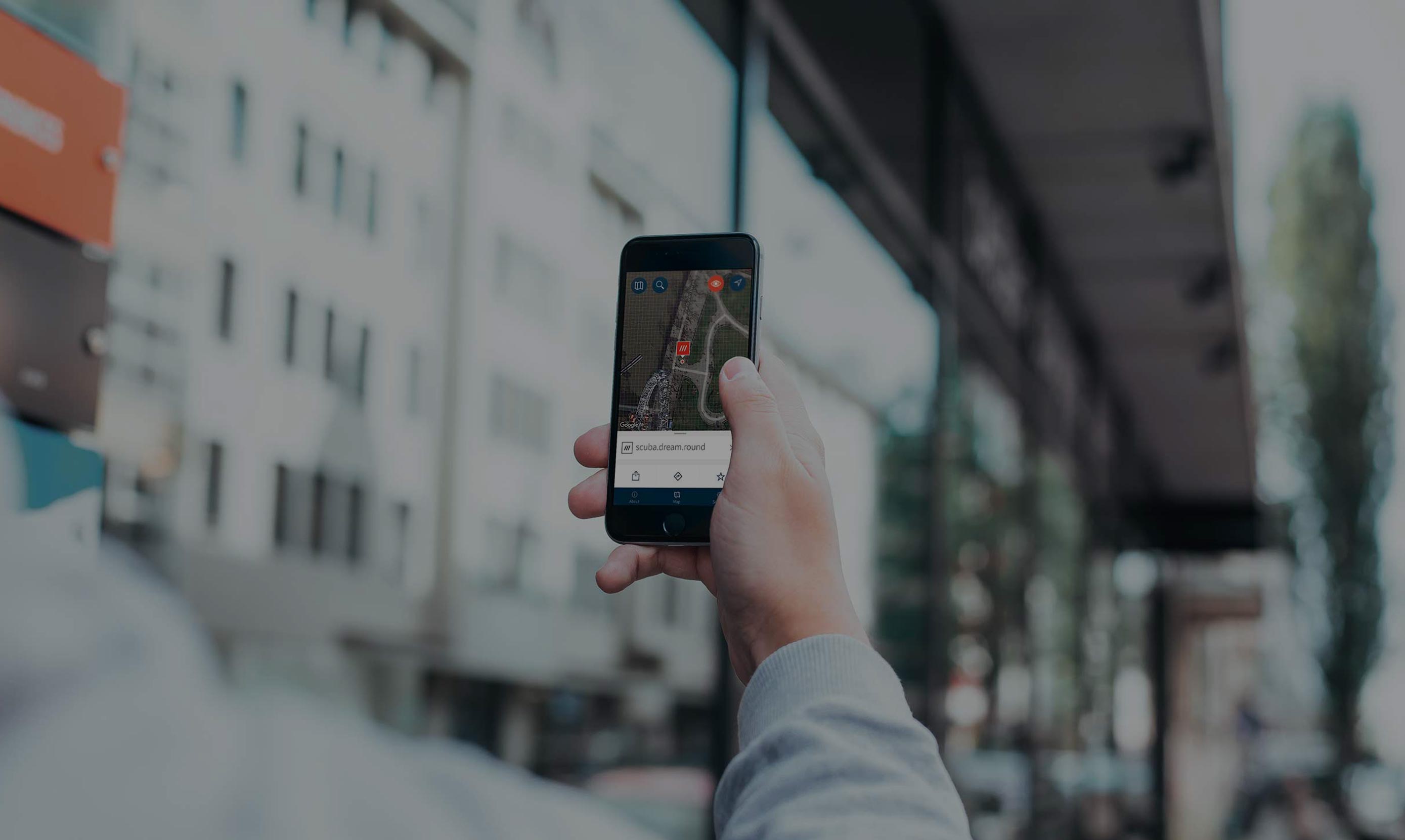 A hand holding a smartphone with the what3words mobile app.