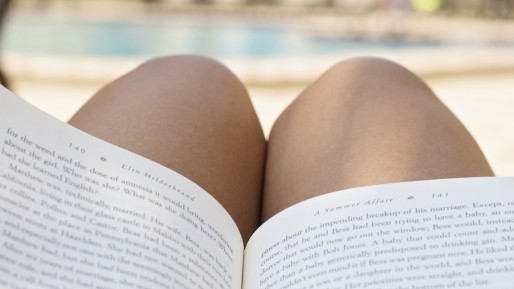 A girl reads a book by the pool