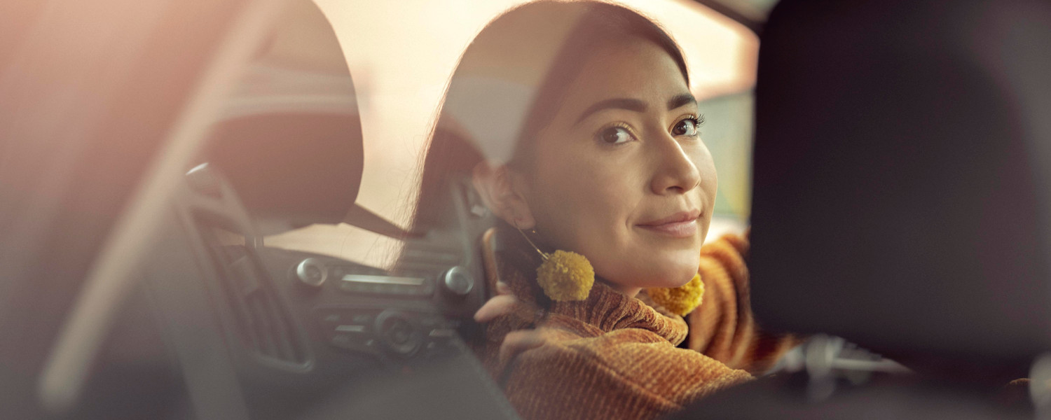 A female Lyft driver smiling in the driver's seat.