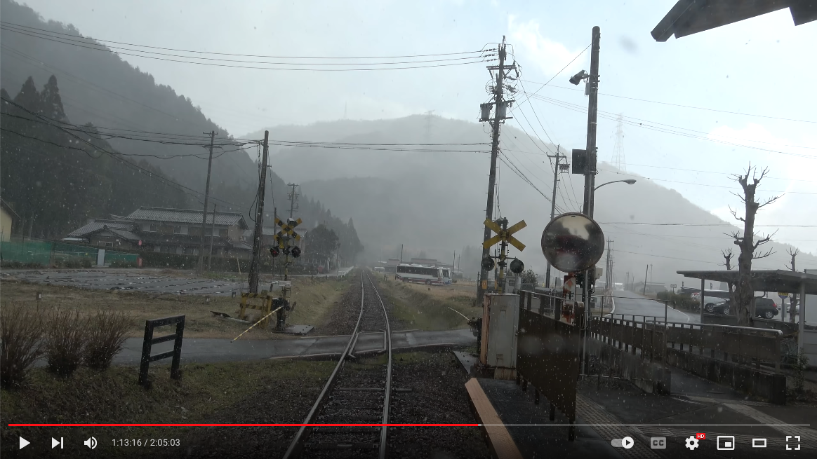 Photographic still from YouTube of a train tracks, signals and mountains in Japan.